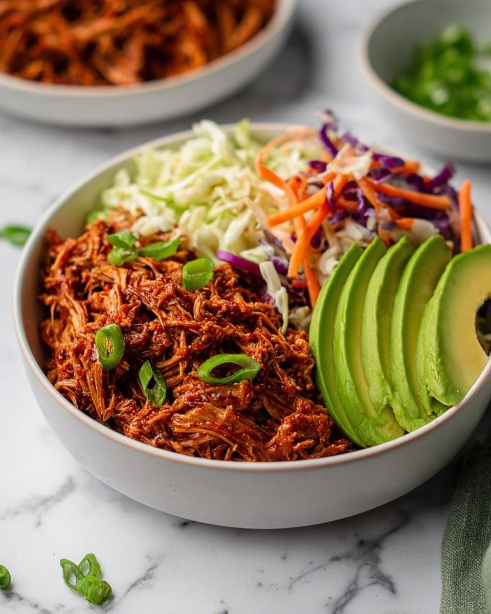 A white bowl with three main layers arranged side by side: on the right, a pile of reddish-brown shredded meat with visible green onion slices on top; in the middle, a mix of shredded white cabbage with thin purple cabbage and orange carrot strips giving a crunchy texture; on the left, three smooth, bright green avocado slices neatly fanned out. The bowl sits on a white marbled surface with a blurred background showing another bowl filled with more shredded meat. A few small green onion pieces are scattered on the surface around the bowl. Photo taken with an iphone --ar 4:5 --v 7