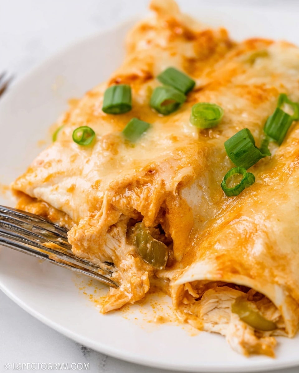 A close-up view of rolled enchiladas on a white plate resting on a white marbled surface, showing three soft, pale golden tortillas covered in melted creamy cheese and light orange sauce, with bits of chunky chicken and small green pieces inside the layers. The top is sprinkled with slices of fresh green onions, and a silver fork is placed near the front of the enchiladas gently pressing into the soft layers. The scene shows a warm, saucy texture with some sauce pooling around the edges. Photo taken with an iphone --ar 4:5 --v 7