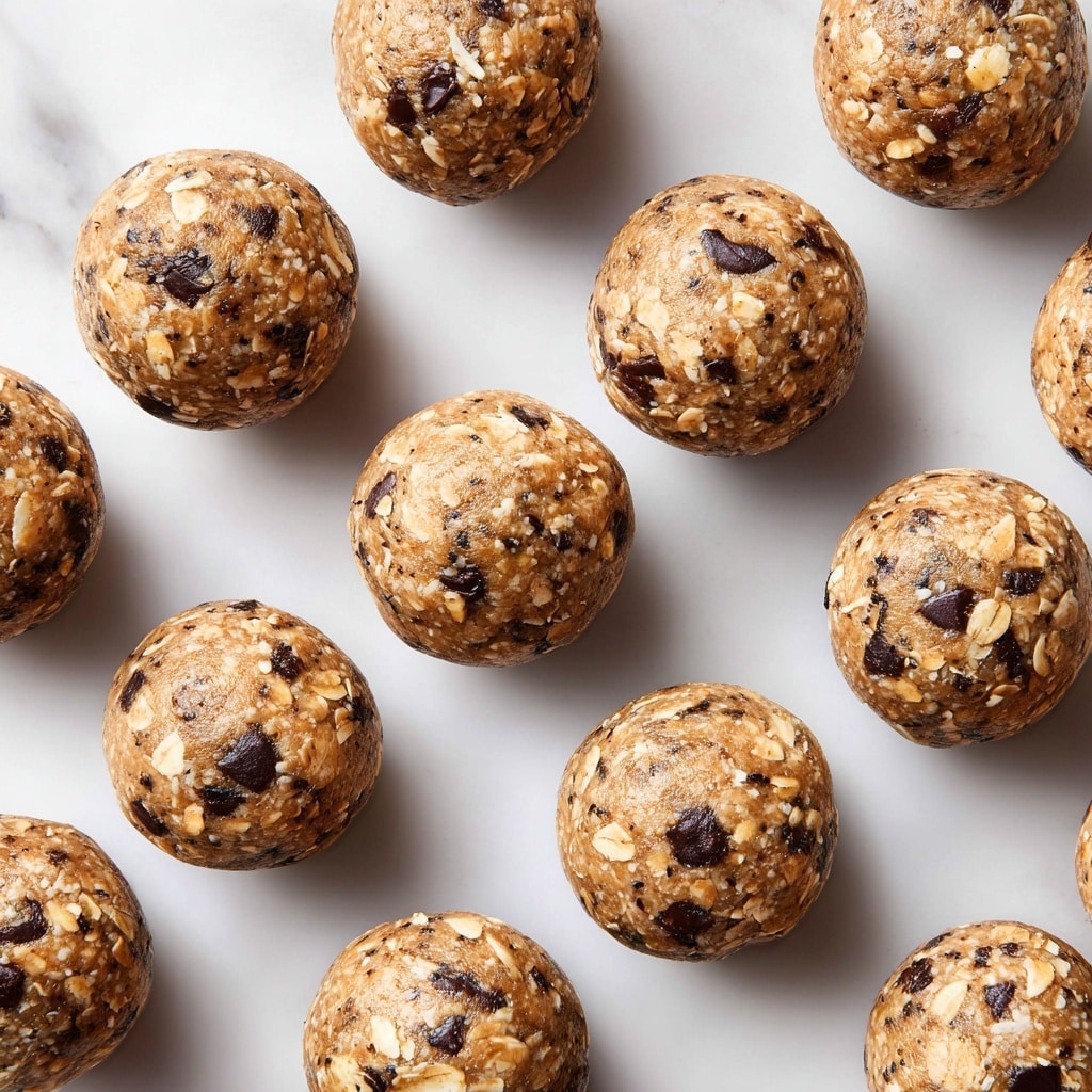 A close-up view of several round energy bites stacked together in a white bowl, each bite showing a rough texture made from oats, dark brown chocolate chips, and small black chia seeds, with a golden-brown base that looks sticky and dense, the mixture is evenly packed and the ingredients clearly visible, placed on a white marbled surface. photo taken with an iphone --ar 4:5 --v 7