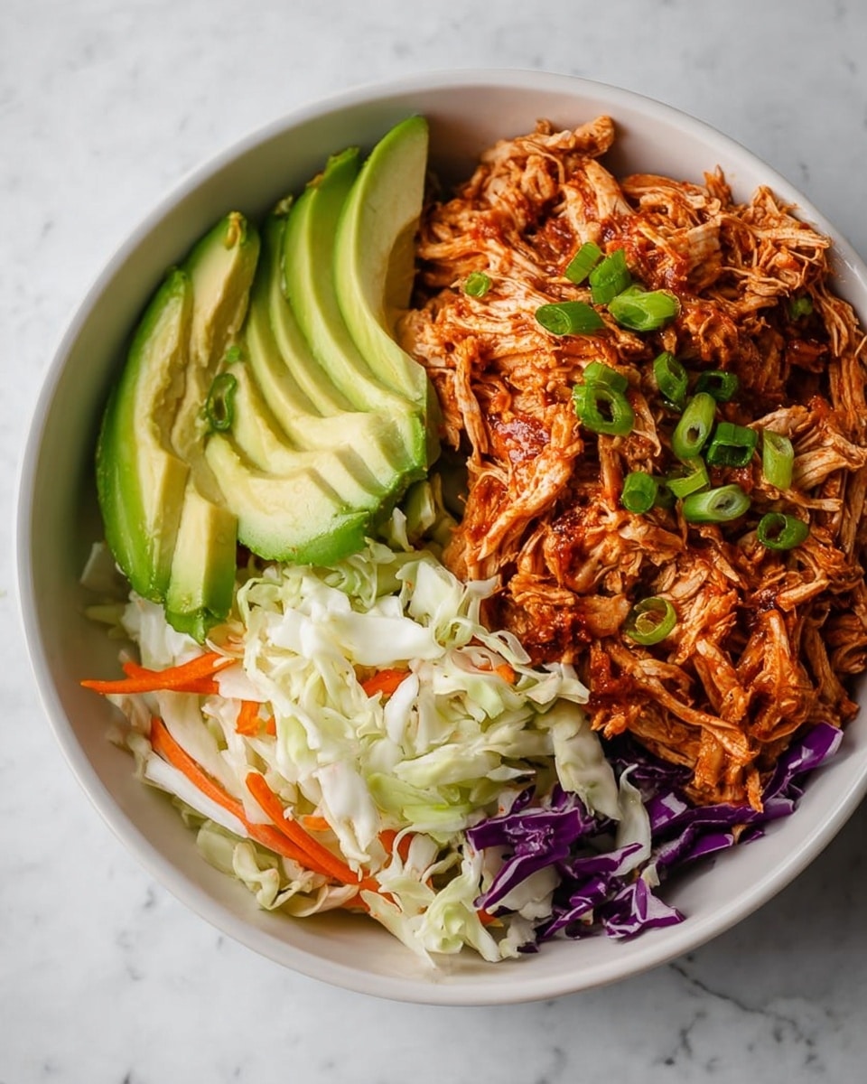 A white bowl sits on a white marbled surface, filled with three main layers of food. On the left side, there is a neat stack of bright green avocado slices with smooth texture. To the right of the avocado, there is a colorful layer of salad made of shredded white cabbage, purple cabbage pieces, thin orange carrot sticks, and small green slices of spring onion, giving a fresh and crunchy look. The largest section of the bowl, on the right side, contains shredded chicken with a reddish-brown sauce, topped with small green onion slices, showing a moist and tender texture. The dish is brightly lit, highlighting the fresh and vibrant colors. Photo taken with an iphone --ar 4:5 --v 7