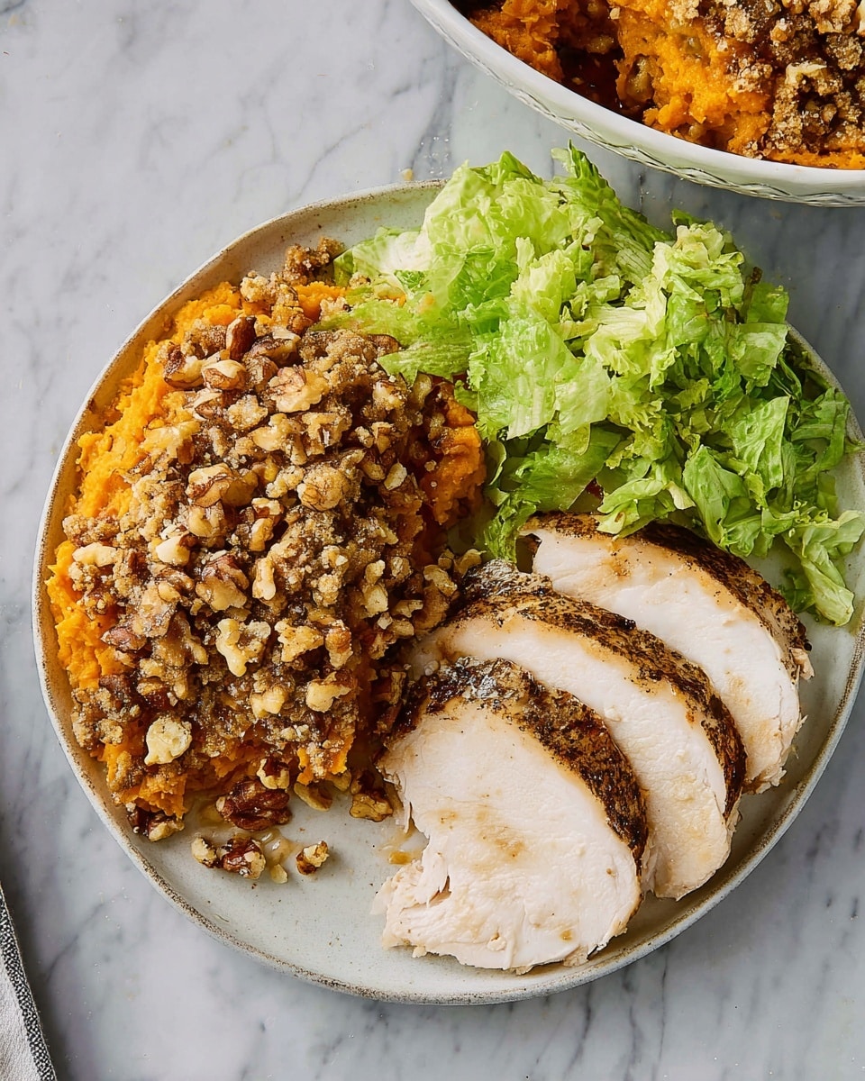 The image shows a white plate with three distinct sections of food on a white marbled surface. On the right side of the plate, there are two slices of roasted turkey breast with a dark seasoned crust and light pinkish-white interior. On the left side, there is a portion of sweet potato casserole topped with chopped walnuts and a crumbly texture, in bright orange color with brown nut pieces on top. At the top of the plate, a small pile of fresh green lettuce leaves is sprinkled lightly with crumbs. In the upper right corner, a corner of a white bowl with more sweet potato casserole is visible. Photo taken with an iphone --ar 4:5 --v 7
