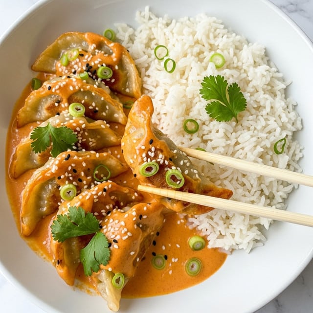 A white bowl holds a dish with two main parts: on the right, a mound of fluffy, white rice with a soft texture, and on the left, several golden-brown dumplings covered in a thick, orange creamy sauce. The dumplings have slightly crispy edges with light browning and are garnished with small green onion rings, white sesame seeds, and fresh cilantro leaves placed on and around them. A pair of light wooden chopsticks holds one dumpling gently in the middle, showing its curved shape and the sauce pooling beneath. The background is a white marbled texture. Photo taken with an iphone --ar 4:5 --v 7