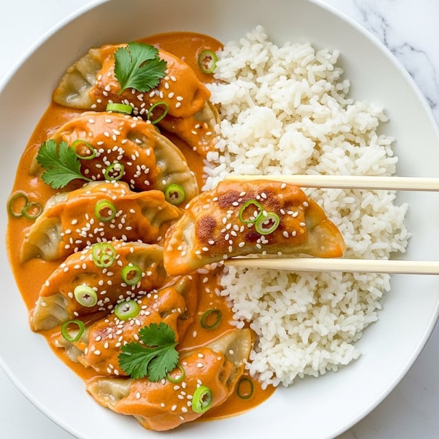 The dish shows a white bowl filled with a base of fluffy white rice on the right side, with a creamy orange sauce covering several golden-brown dumplings layered on the left; the dumplings are slightly crispy at the edges and soft in the middle, topped with scattered green onion slices, white sesame seeds, and bright green cilantro leaves for garnish. A pair of light wooden chopsticks is lifting one dumpling, showing the smooth texture of the sauce that clings to the dumpling. The bowl sits on a white marbled surface that adds a clean, fresh look to the presentation. photo taken with an iphone --ar 4:5 --v 7