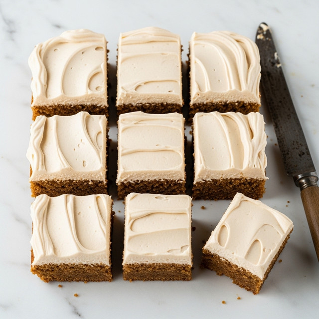 The image shows nine square pieces of a dessert arranged in a 3x3 grid on a white marbled textured surface. Each piece has two layers: a bottom layer of moist, light brown cake and a thick top layer of creamy, light beige frosting with a smooth, slightly whipped texture and soft swirls. The edges of the cake layer are neatly cut, and the frosting layer extends smoothly to the edges with subtle peaks and curves. One piece in the bottom right corner is slightly separated from the rest. There is an old knife with a wooden handle resting beside the dessert. photo taken with an iphone --ar 4:5 --v 7