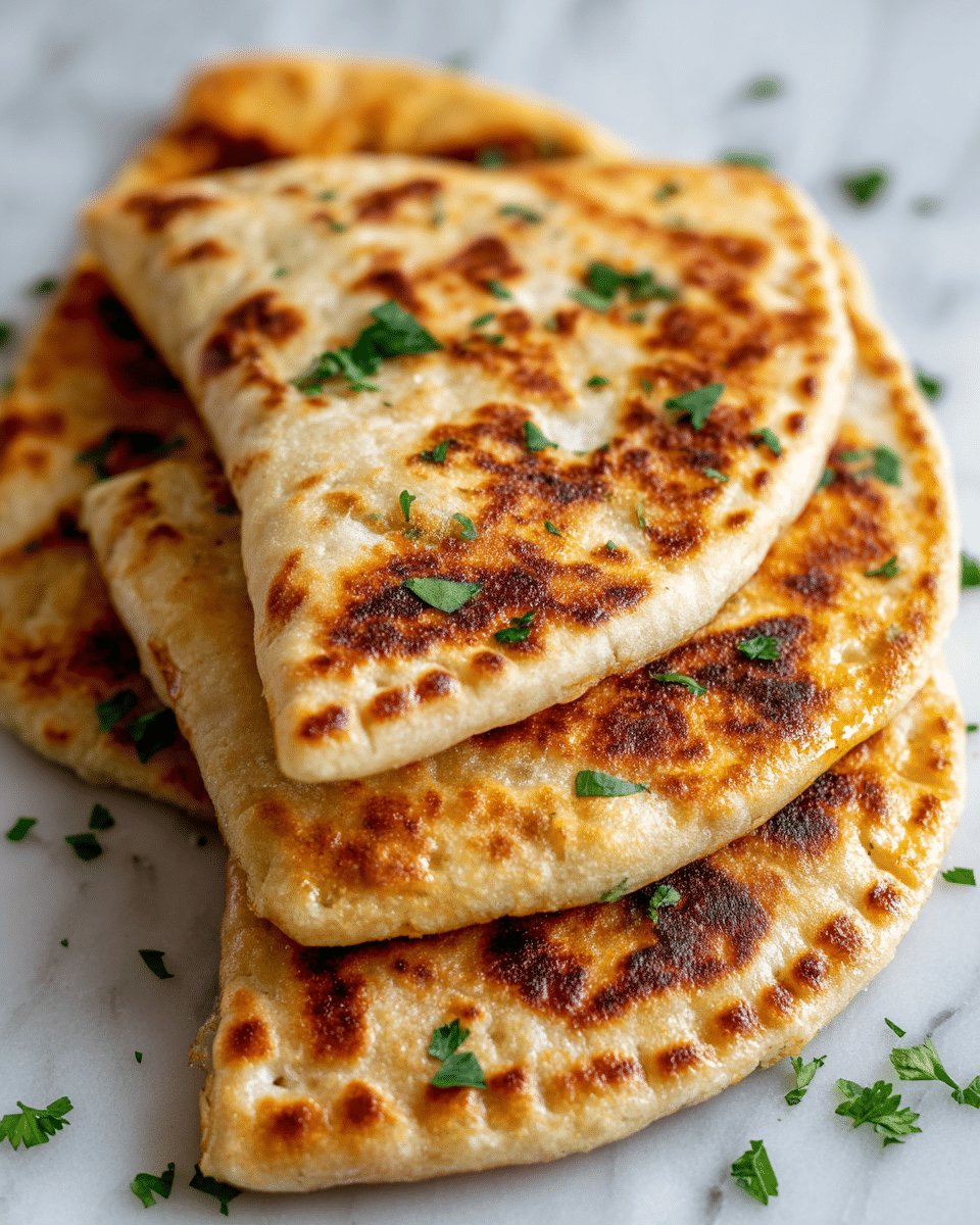 Three crispy, golden-brown half-moon shaped flatbreads are layered slightly on top of each other on a white marbled surface. Each flatbread has a puffy, bubbly texture with darker golden spots that show where they were cooked. Small green parsley leaves are scattered on the flatbreads and around them on the surface, adding a fresh touch of color. The edges of the flatbreads are pressed down with fork marks, giving a neat, sealed look. photo taken with an iphone --ar 4:5 --v 7
