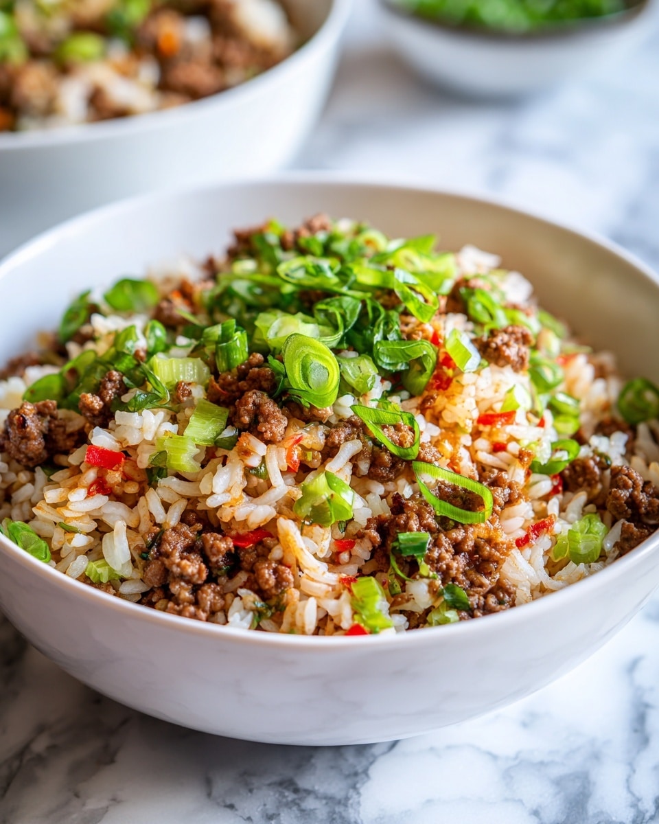 A close-up view of a bowl filled with a mixed dish showing one main layer of cooked white rice combined with small pieces of browned ground meat, golden-brown crispy meat chunks, and green chopped scallions scattered evenly on top, mixed with small bits of celery and red peppers adding splashes of color. The bowl is white, and the background features a white marbled texture. Photo taken with an iphone --ar 4:5 --v 7