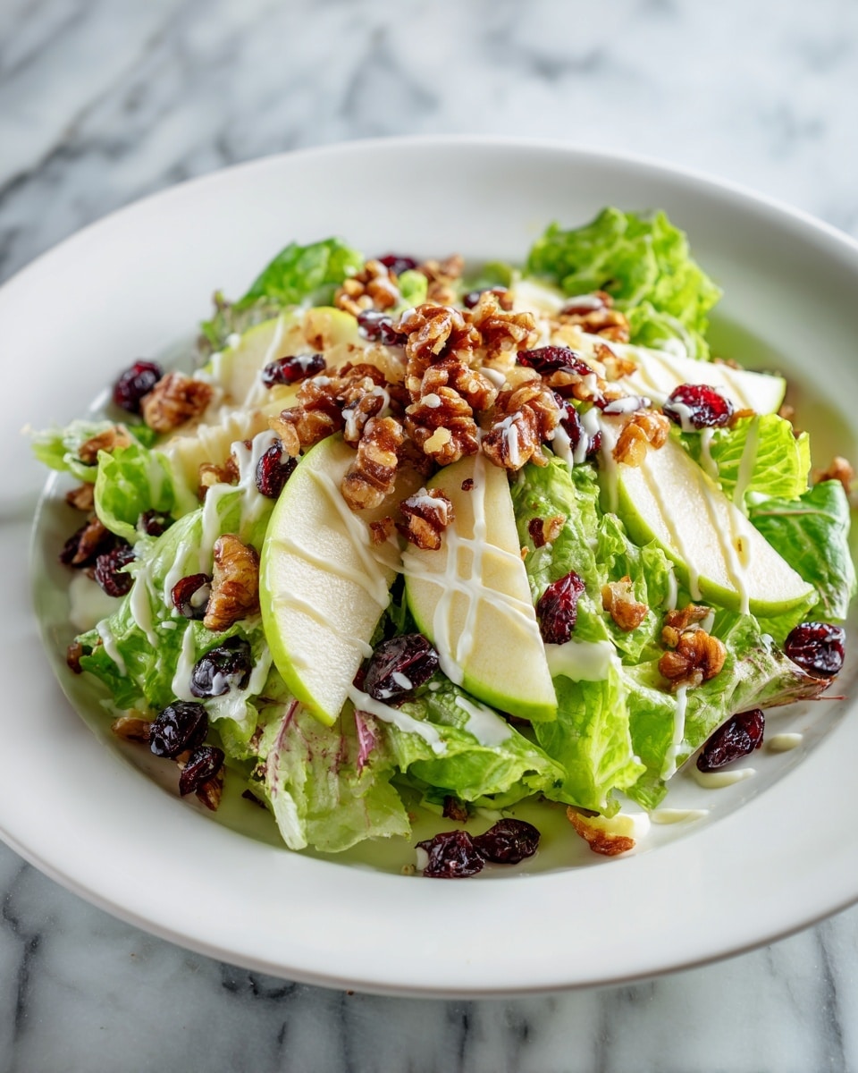 A fresh salad served on a white plate, placed on a white marbled surface, features multiple layers starting with a base of bright green leafy lettuce with soft, curly edges. On top of the lettuce, there are thin, pale green apple slices spread evenly around. Scattered across the salad are medium brown pecan halves adding texture and depth, along with small, dark red dried cranberries providing pops of color. The whole salad is lightly drizzled with creamy white dressing that contrasts with the greens and nuts. Photo taken with an iphone --ar 4:5 --v 7