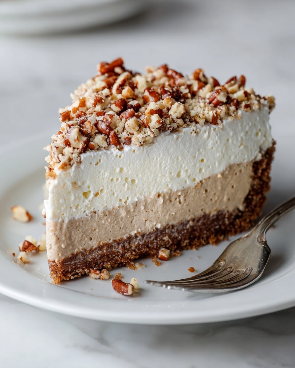The image shows a slice of pie on a white plate with a white marbled texture surface. The pie has three layers: the bottom layer is a thick, crumbly brown crust; the middle layer is a light tan, smooth filling; and the top layer is thick, white, fluffy whipped cream. The top of the pie is covered with chopped pecans that add a crunchy texture. There are some crumbs scattered on the plate, and a metal fork is placed on the right side of the plate. photo taken with an iphone --ar 4:5 --v 7