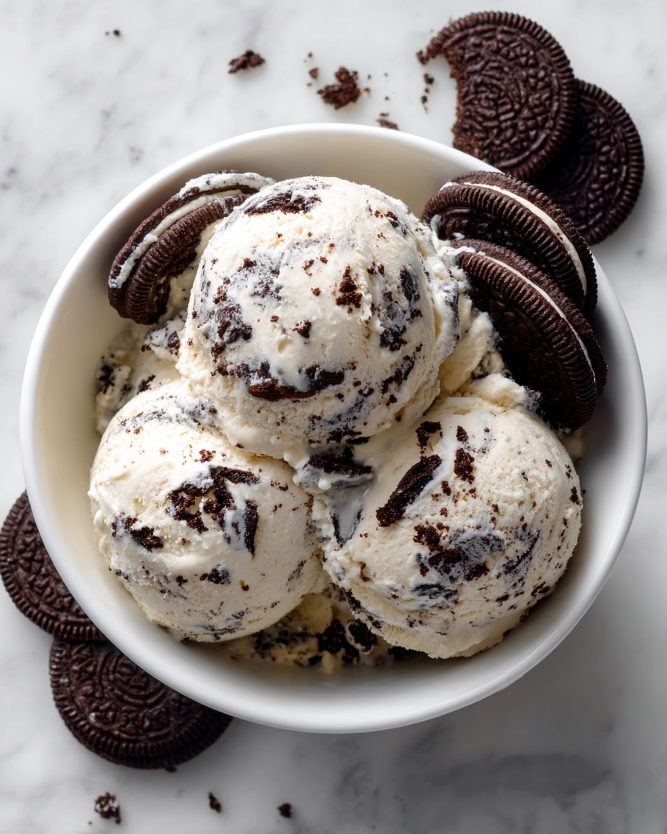A white bowl holds three scoops of cookies and cream ice cream, each scoop showing creamy white ice cream mixed with dark chocolate cookie pieces. The scoops are stacked so one sits partly on top of the other two, creating a rounded, inviting shape. On the side, partially visible, are two dark chocolate sandwich cookies with white cream filling, adding contrast to the creamy texture of the ice cream. The whole setup sits on a white marbled surface, giving a clean and fresh look. photo taken with an iphone --ar 4:5 --v 7