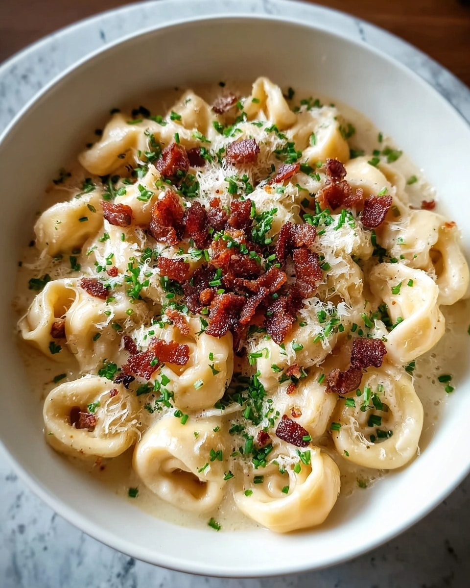 A white bowl filled with three layers of tortellini pasta covered in creamy pale yellow sauce, scattered with small pieces of crispy dark brown bacon on top. The dish is finished with a sprinkle of grated white cheese and small green herb bits, sitting on a white marbled surface. photo taken with an iphone --ar 4:5 --v 7
