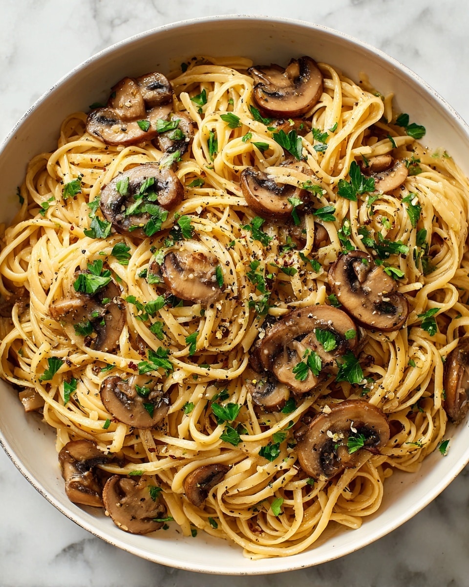 A close-up view of creamy fettuccine pasta spread evenly in a white deep pan. The pasta is coated with a light beige creamy sauce, mixed with soft, thinly sliced mushrooms in light brown color. Sprinkled on top are small pieces of bright green parsley and finely chopped herbs, adding a fresh contrast to the dish. The pasta strands twist and curl loosely across the pan, showing a smooth and rich texture photo taken with an iphone --ar 4:5 --v 7
